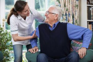 Two older adults and a staff member sharing a light conversation in a sunny common room.