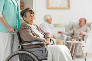 Older adult using a walker enters an accessible vehicle with assistance near an assisted living residence.